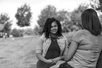 Teenager sitting on a park bench with her mom