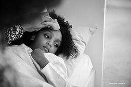 Child laying in bed with wet towel pressed against their forehead