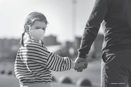 child wearing a mask holding an adult's hand