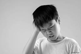 child holding one hand up to their head.