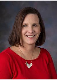 Portrait of Amy Donegan, PCPNP. Amy has short brown hair, a red shirt and silver necklace on. The background is a mix of dark and light grays.
