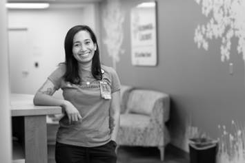 Janette is standing in a waiting room, resting one arm on a counter.