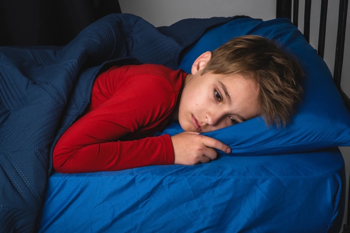young boy lying in bed