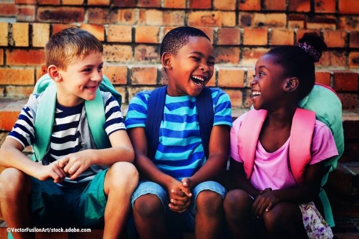 3 kids smiling and laughing with bookbags on