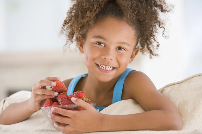 young child holding a bowl of strawberries
