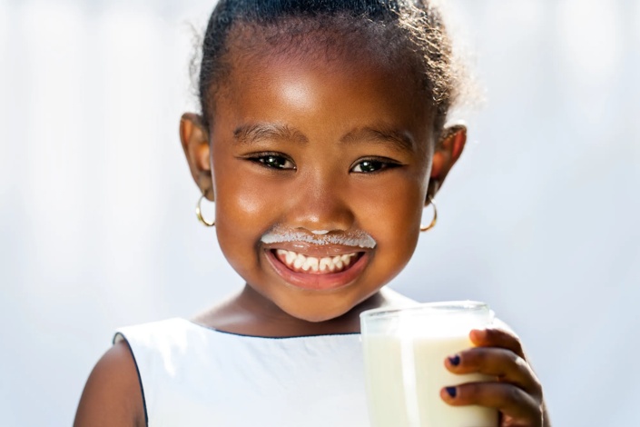 young child drinking a glass of milk