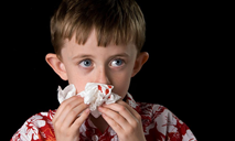 Child stopping a nosebleed with a tissue.