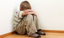 child sitting in the fetal position with his head to his knees