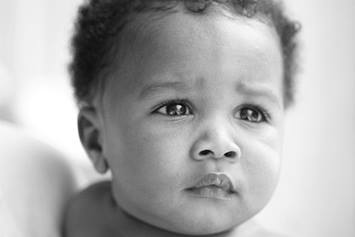 Baby staring near the camera while being held in parent's arms