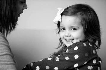 young girl wearing a bow in her hair and polka dots smiling at the camera