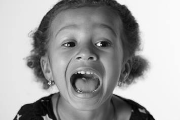 Child opening mouth wide for tonsillectomy check.