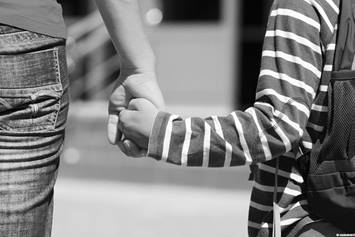 Child wearing a backpack holding parent's hand