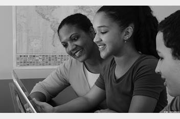 Two kids and their mom looking at a tablet