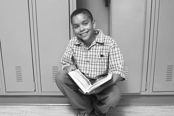 Child squatting by locker, reading a book