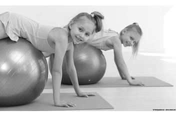 Two girls exercising using stability ball.