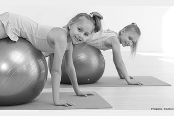 Two girls exercising using stability ball.