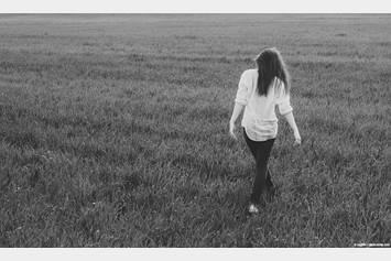 Teenage girl walking through a field of grass.