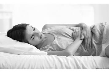 Teenage girl laying in bed with stomach cramps.