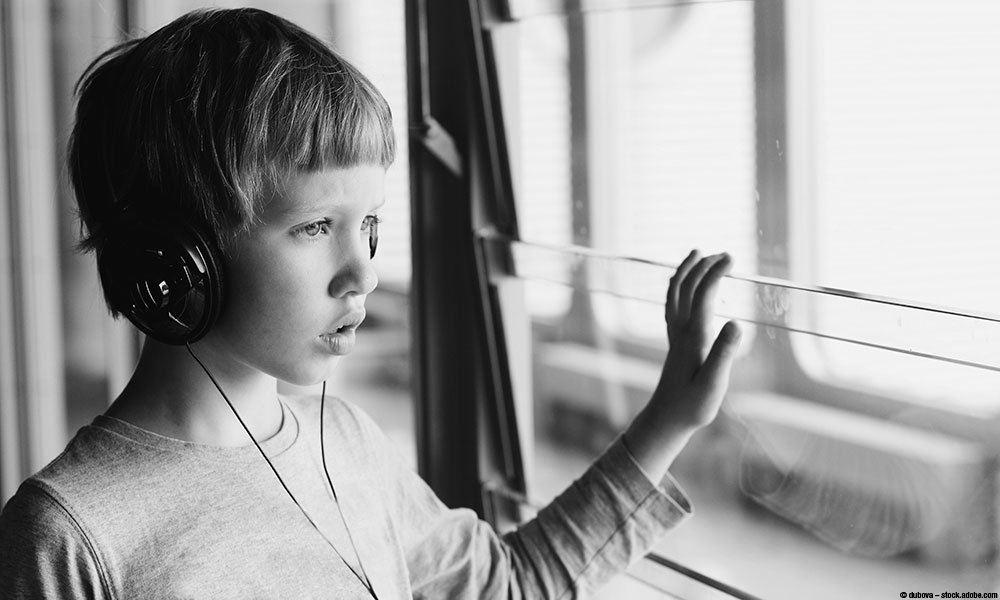 image of boy with headphones on looking out a window