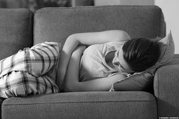 image of girl lying on a couch holding her stomach
