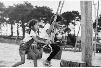 One kid pushing another kid on a swing set