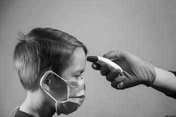 Child wearing a mask having his temperature taken