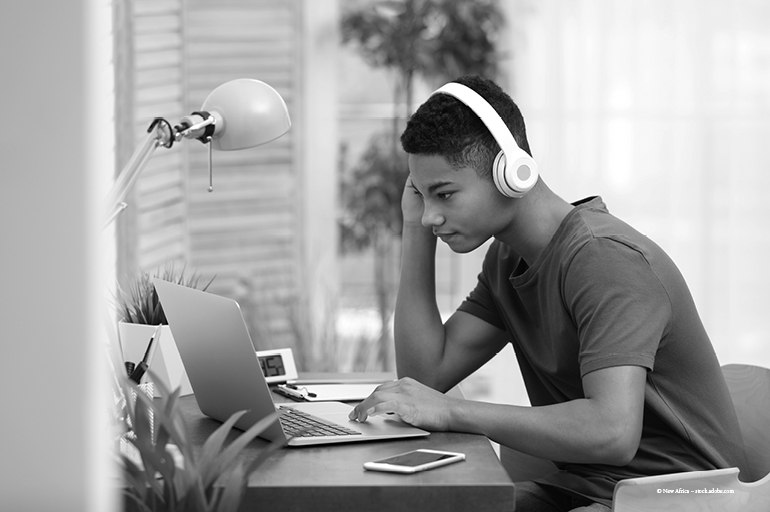 Teen wearing headphones and working on laptop