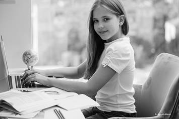 Child sitting in office chair typing on a laptop