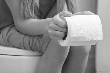 child sitting on a toilet holding toilet paper