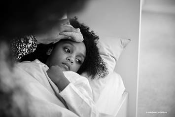 little girl looking sick and laying in bed.