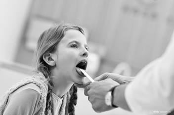 Child having throat medically examined.