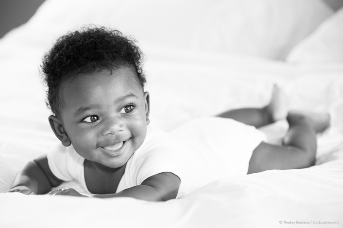 infant on their stomach in a white onesy