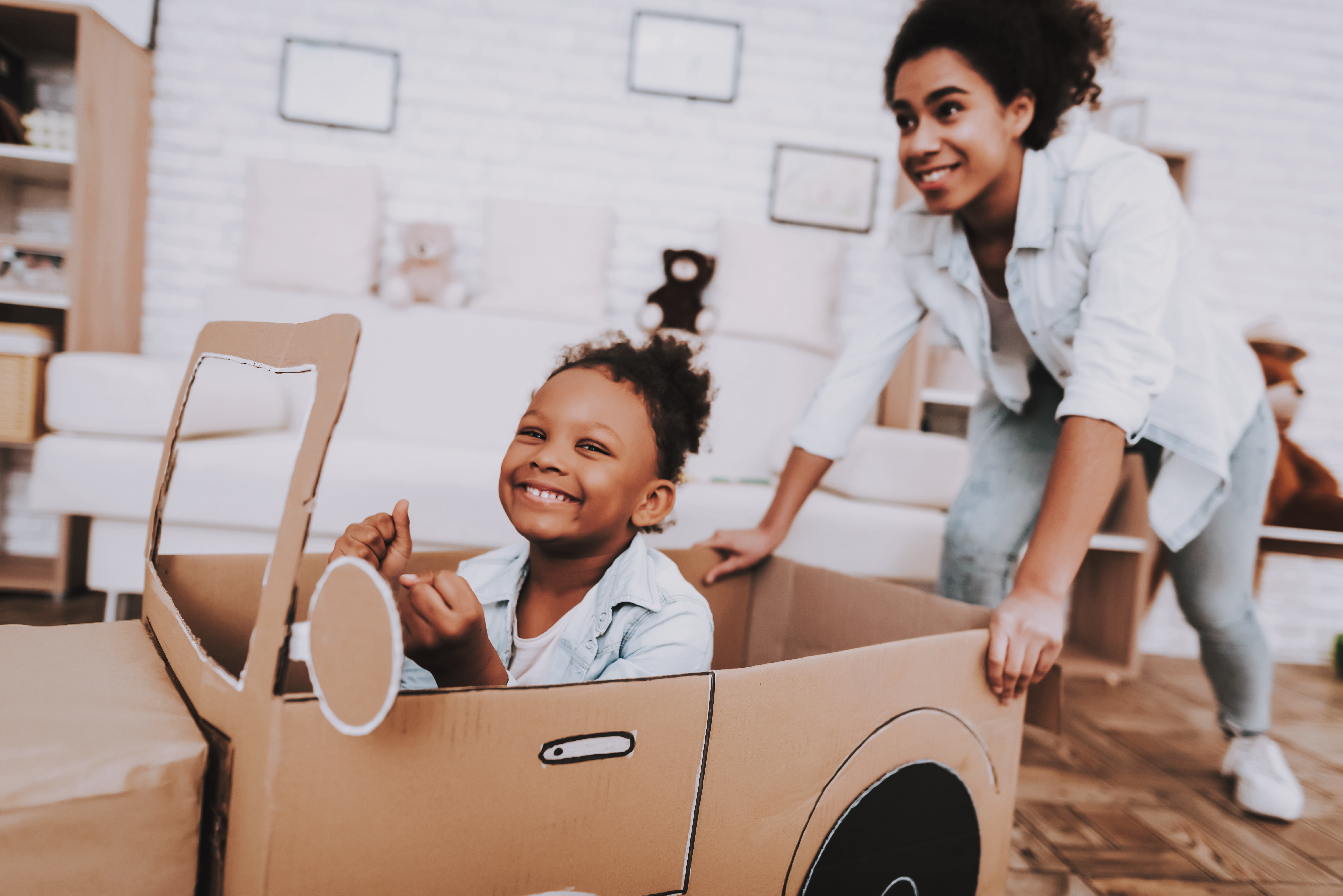 lady pushing a little girl in a cardboard wagon