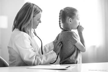 doctor listening to a young girl's lungs with a stethoscope