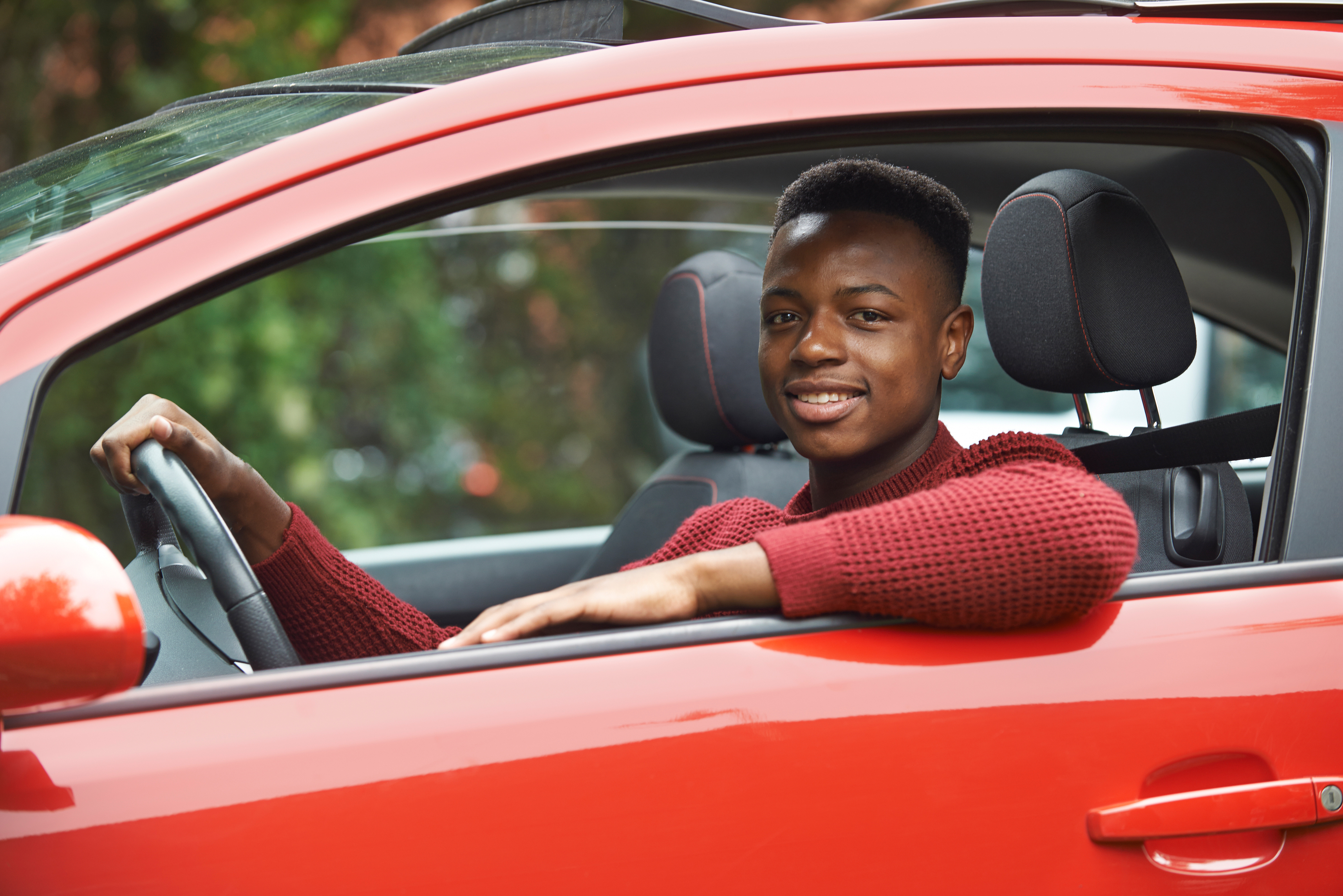 teen in the driver's seat of a car looking at the camera