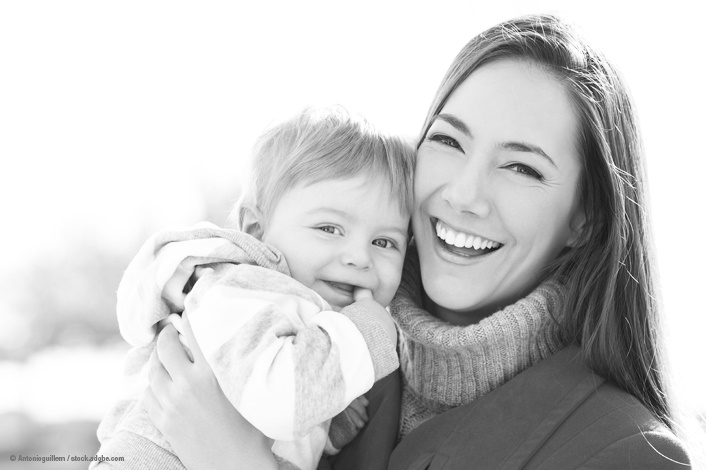 mother holding child, both dressed in winter clothing and laughing