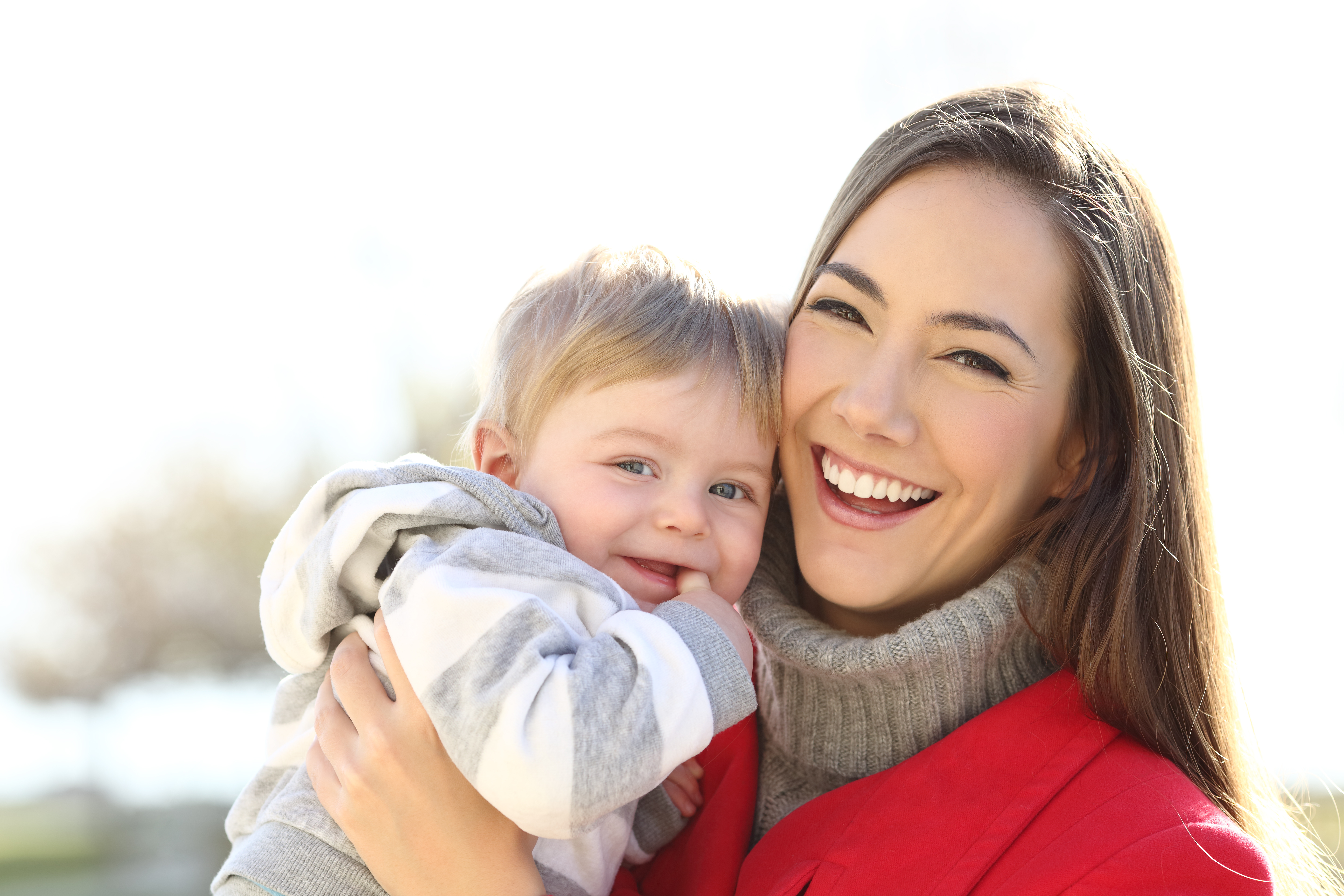 mother holding child, both dressed in winter clothing and laughing