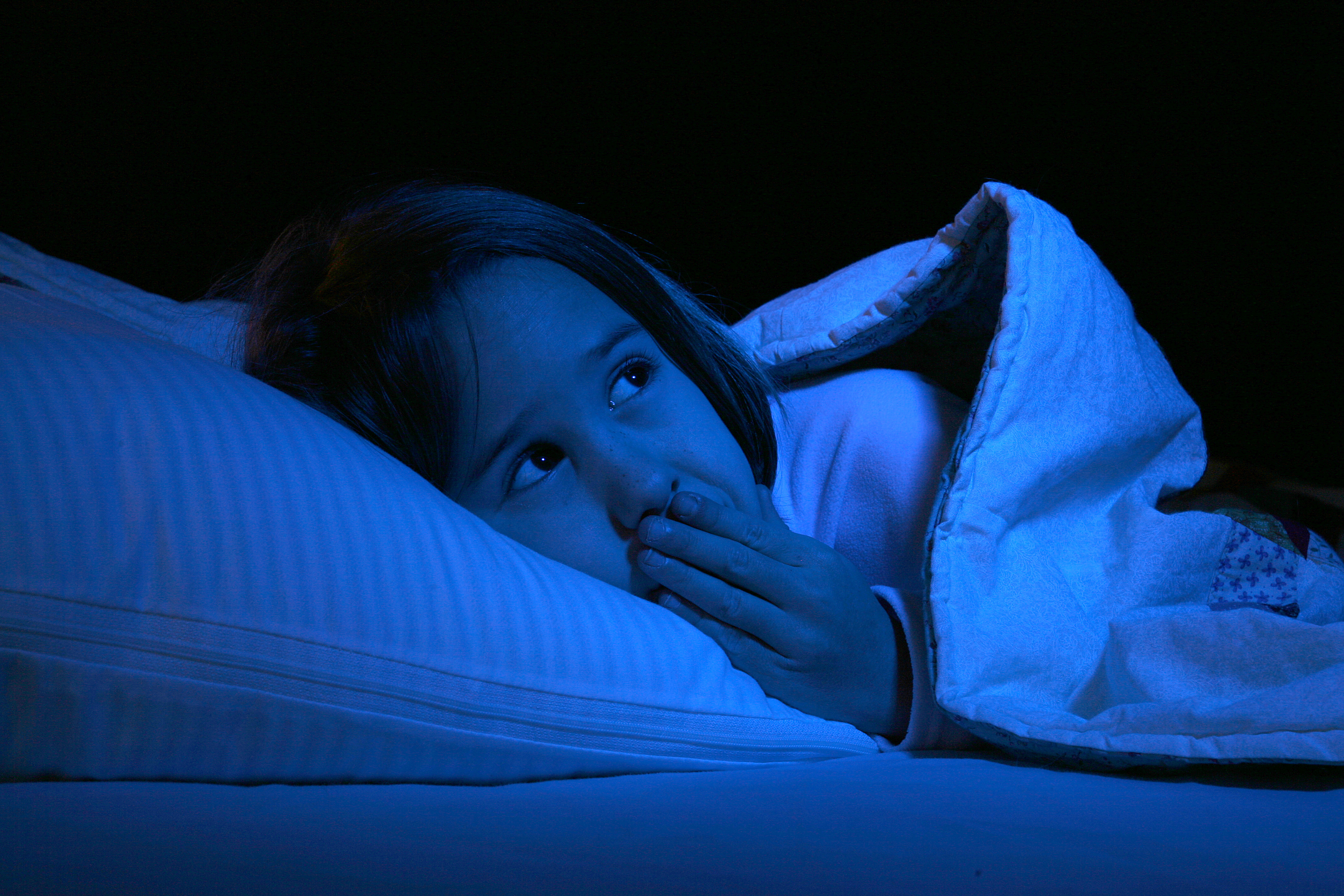 child laying in bed, but looking around nervously