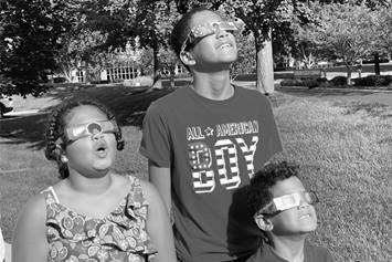 three kids looking upwards towards the solar eclipse