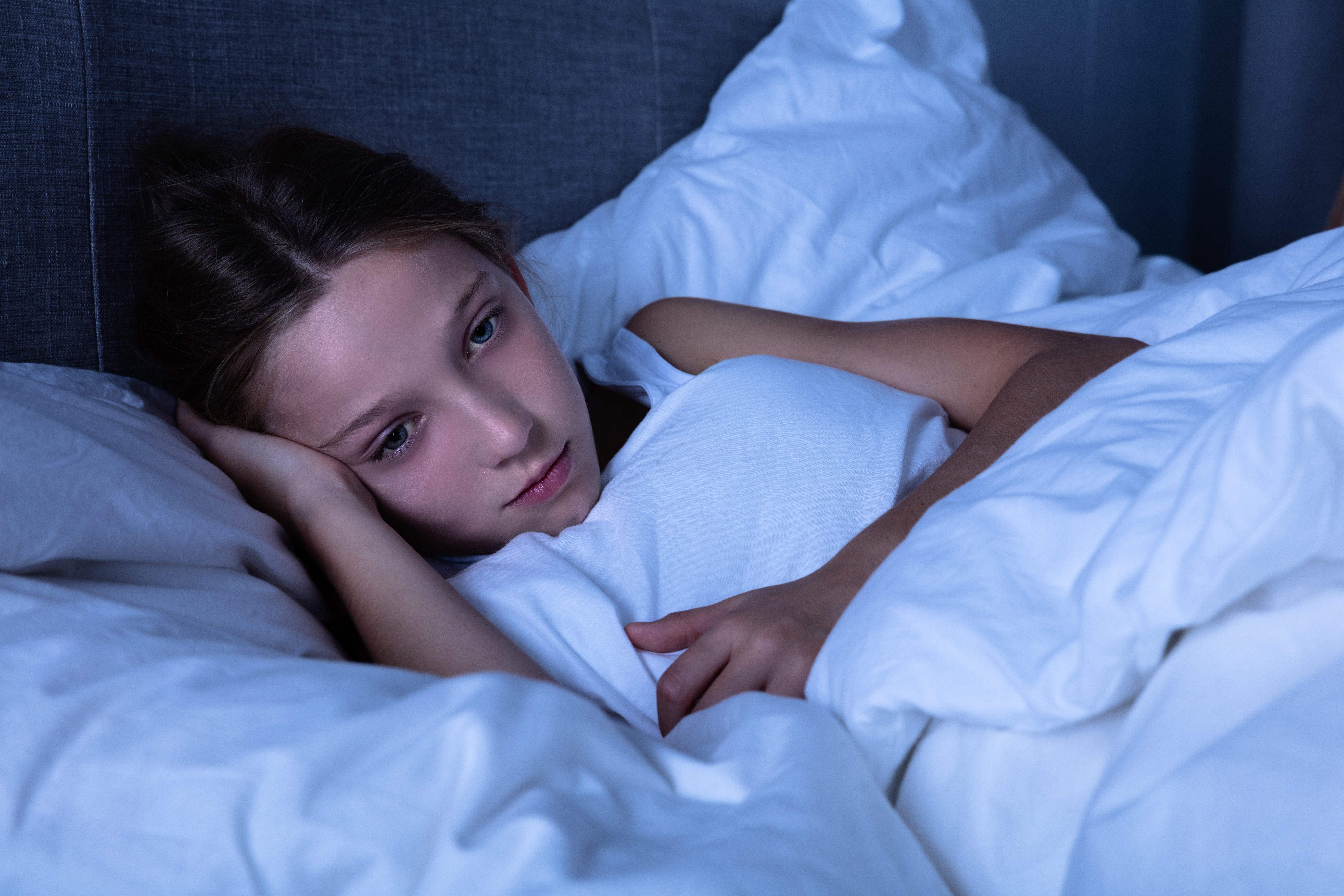 child laying in bed looking exhausted