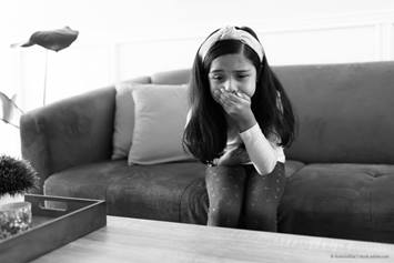 young girl sitting on a couch looking like she might vomit