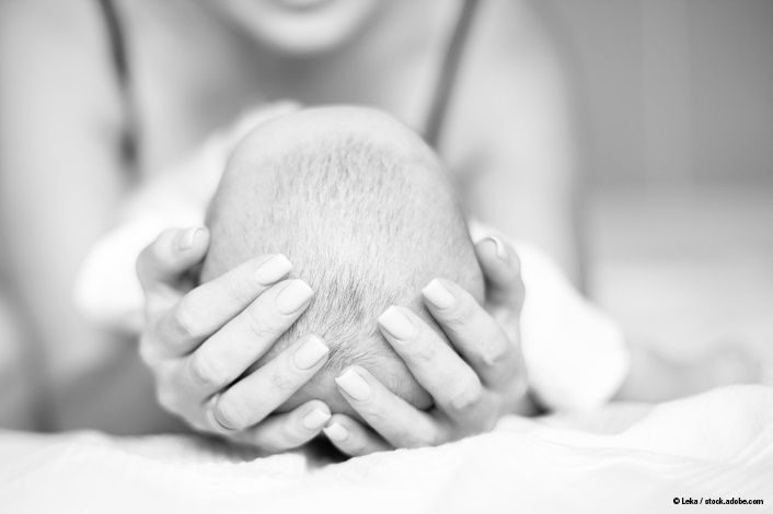 mother cradling a baby's head in her arms