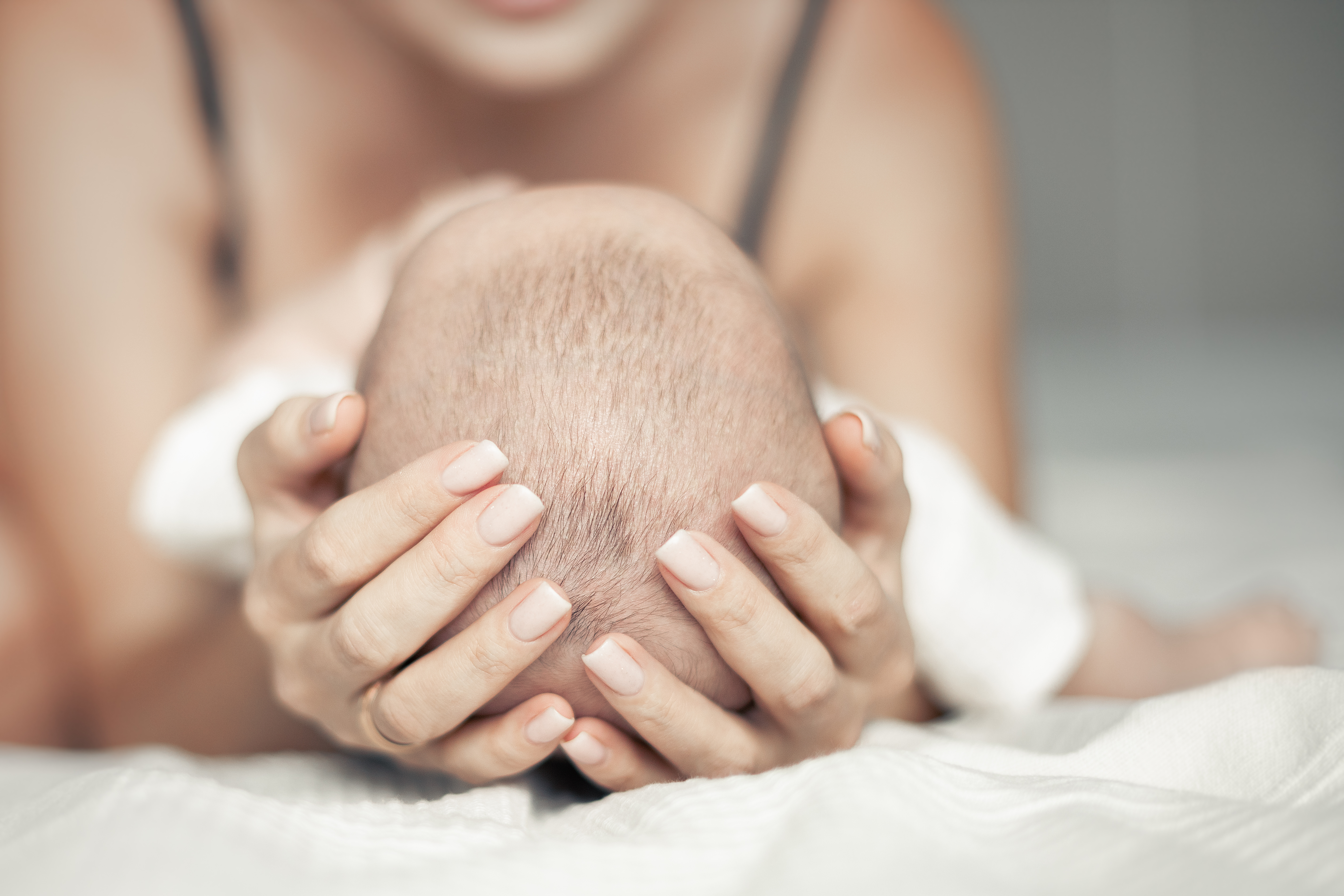 mother cradling a baby's head in her arms