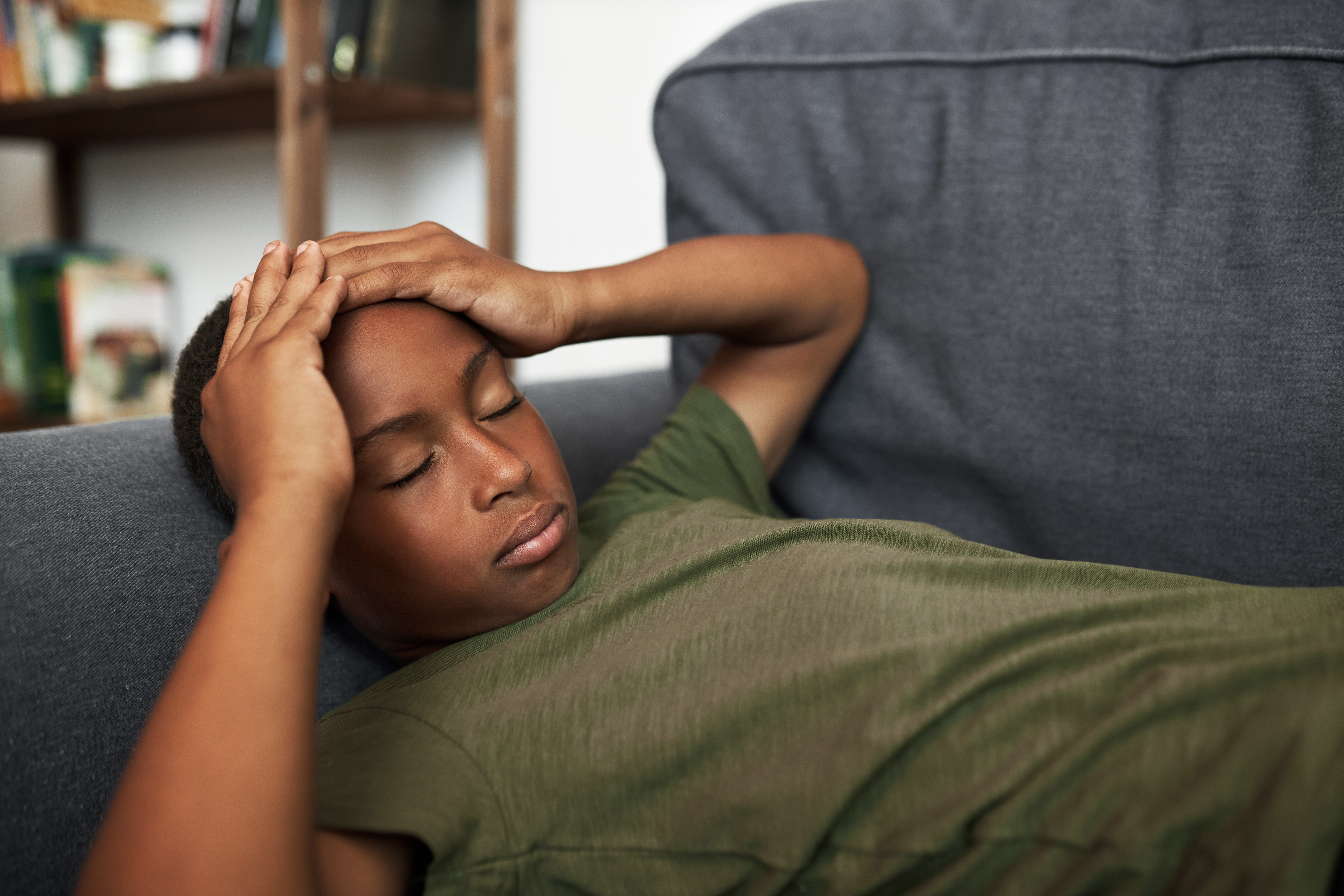 boy laying down grabbing his head