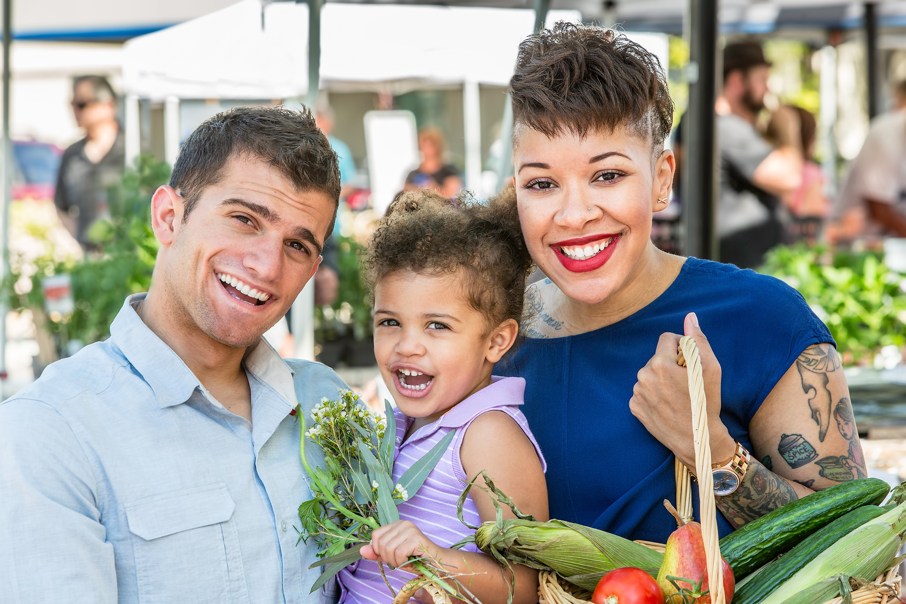 man and woman smiling and holding their child