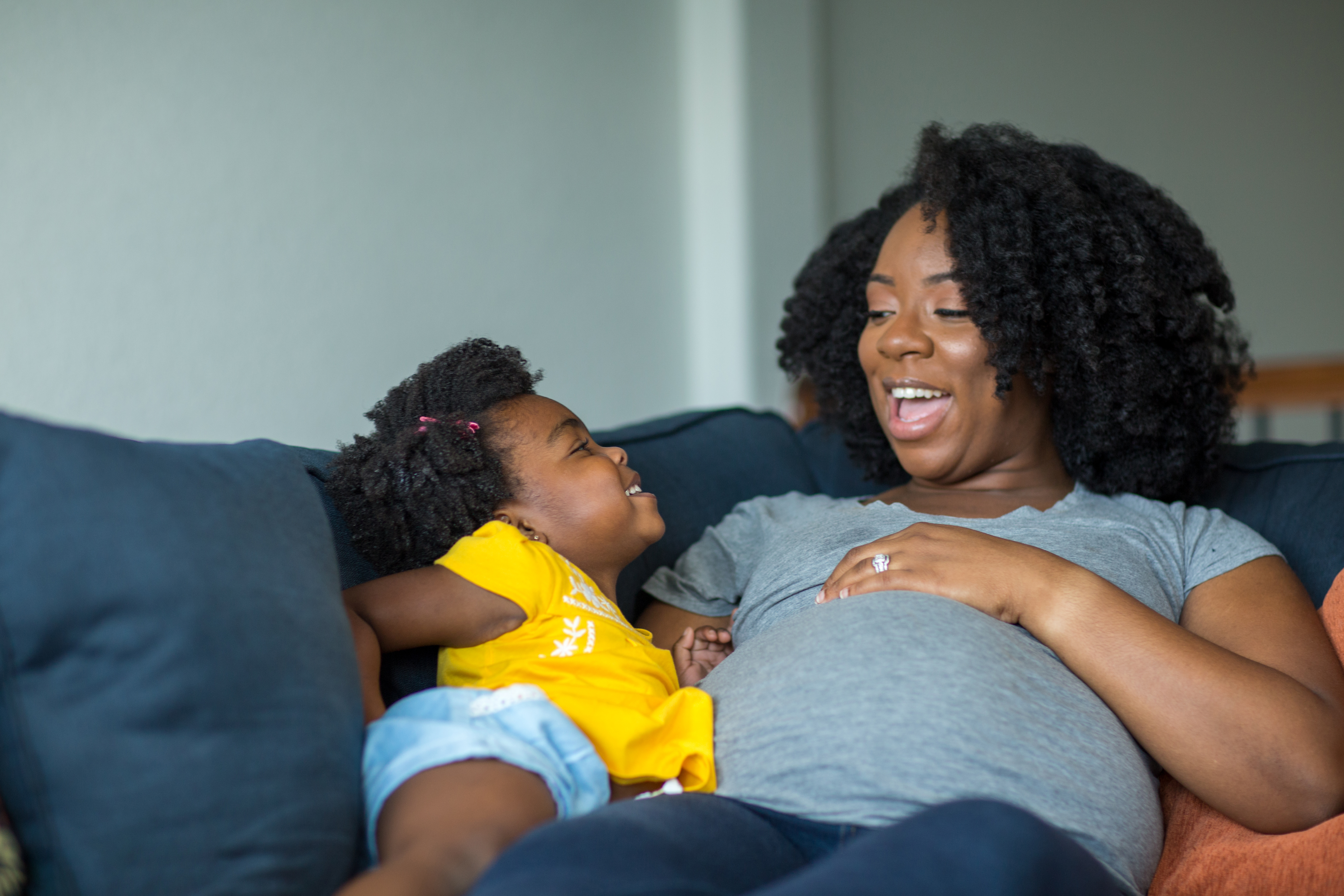 mother and child sitting on the couch smiling