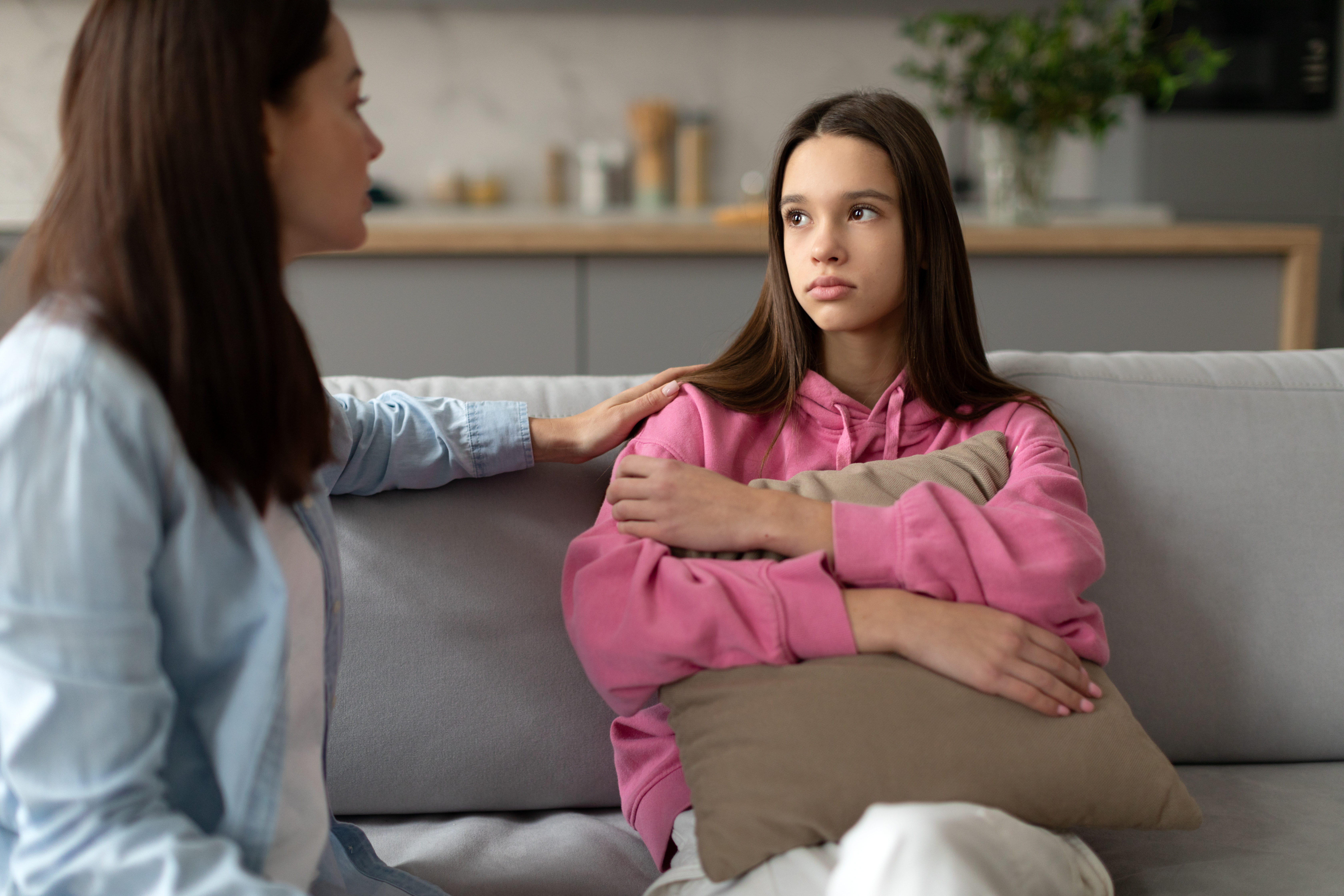 mother and daughter are talking seriously on a couch
