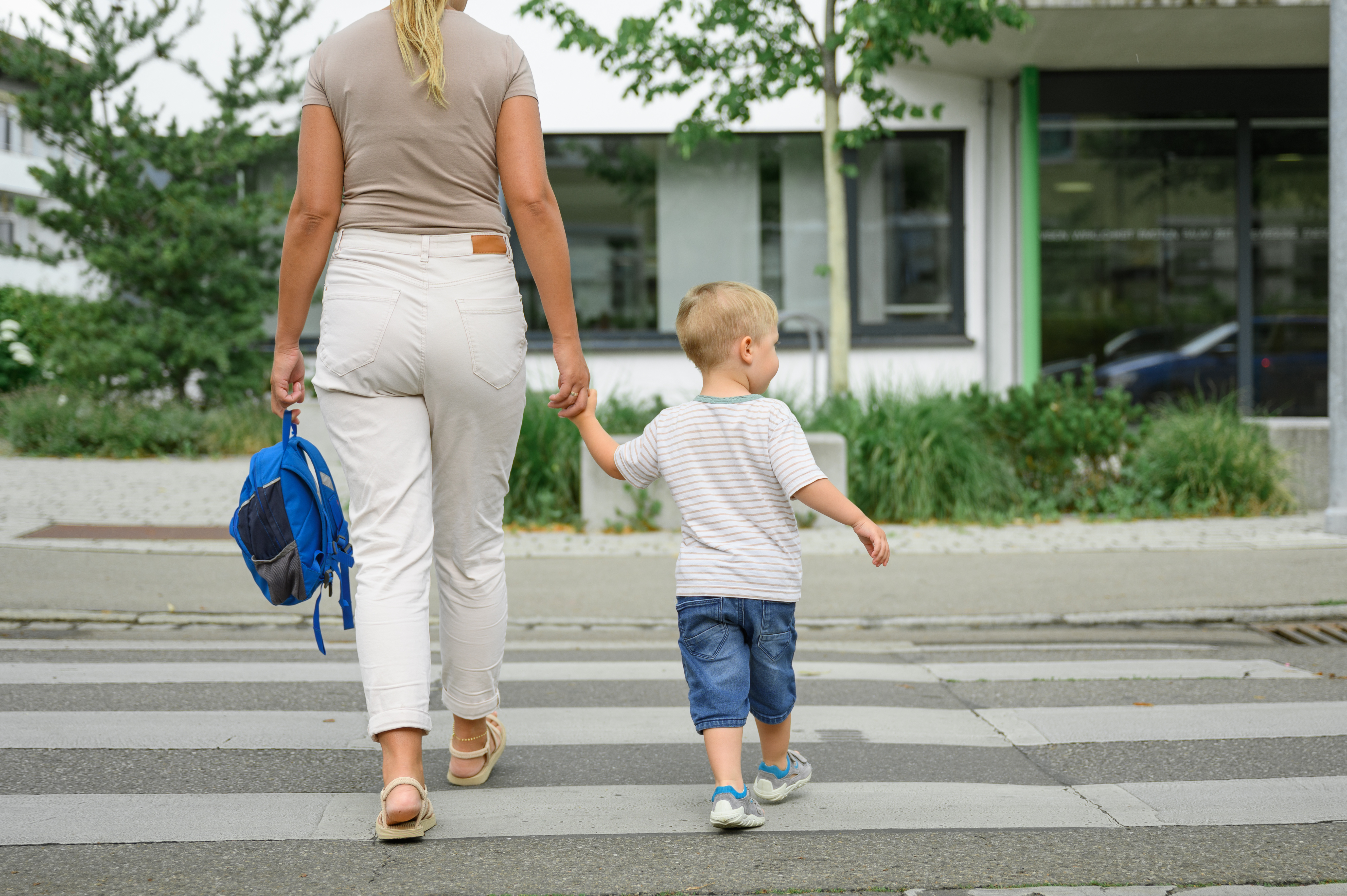 adult and child holding hands and crossing the street