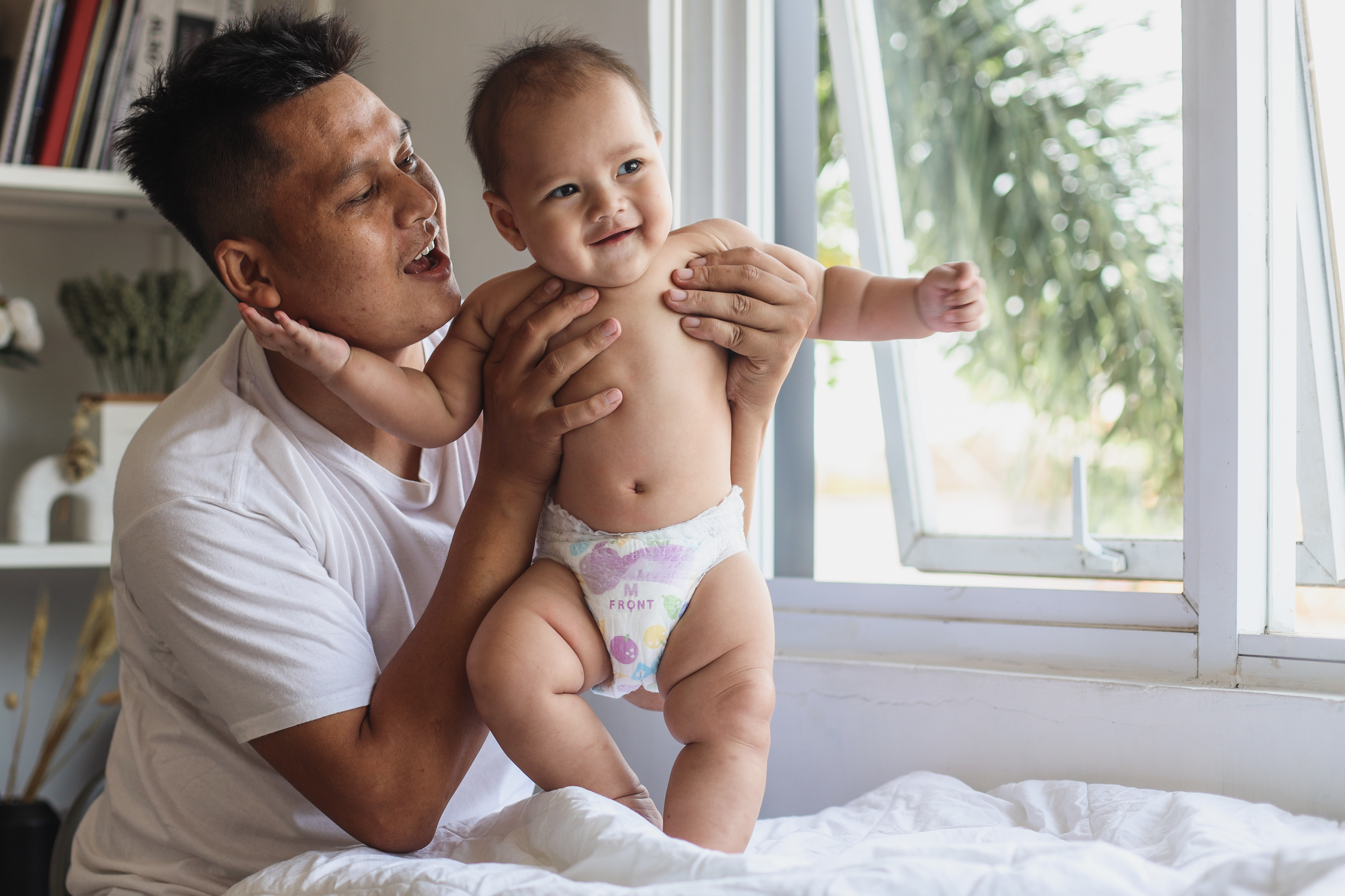 parent holding baby in a diaper and smiling