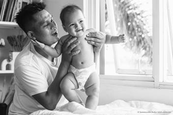 parent holding baby in a diaper and smiling